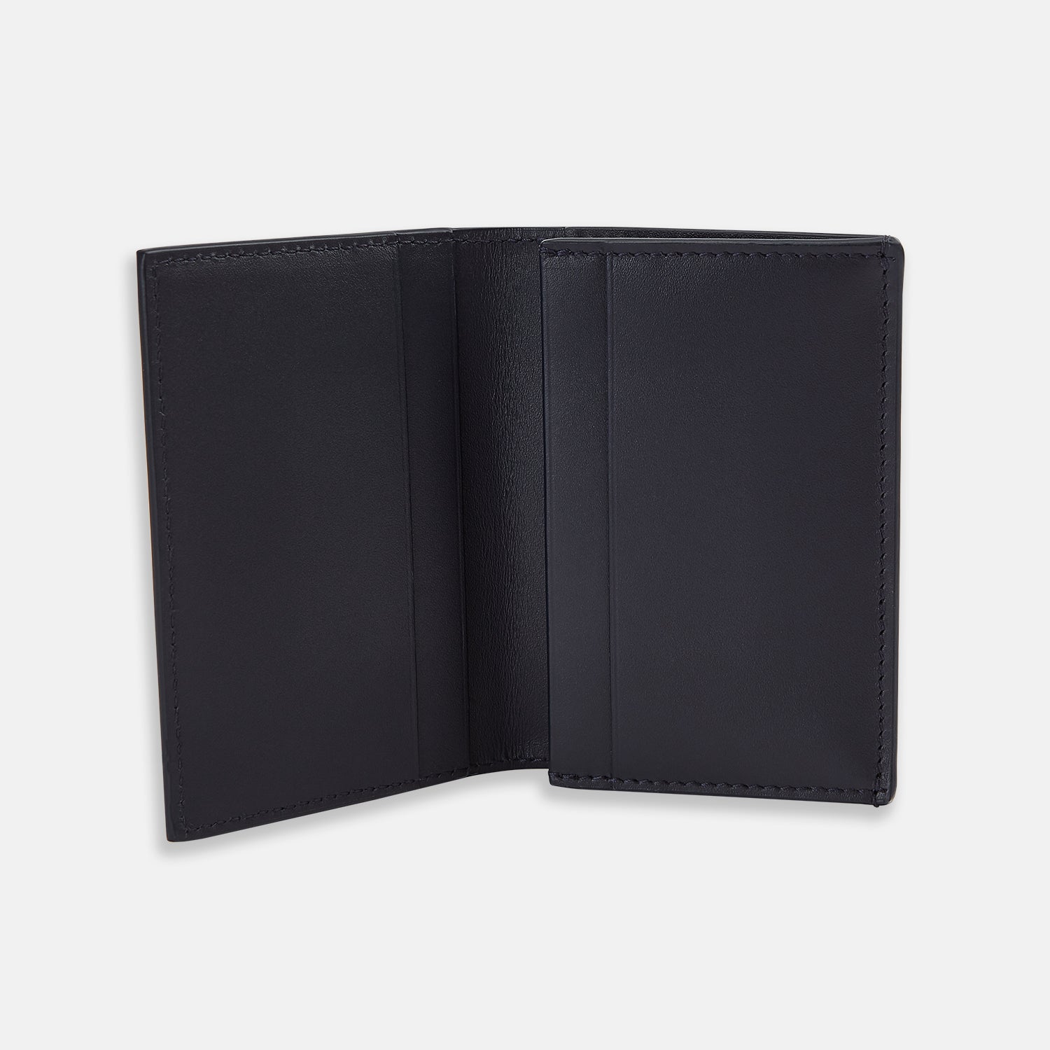 View 2 of product A navy, full-grain leather bi-fold card holder by Turnbull & Asser lies open and empty on a plain white background, showcasing simple stitching and two main visible compartments.