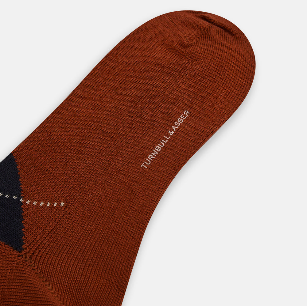 The Turnbull & Asser Rust Wool Check Mid-Length Sock features a brown wool design with black, gray, and orange checks, shown on a white background.