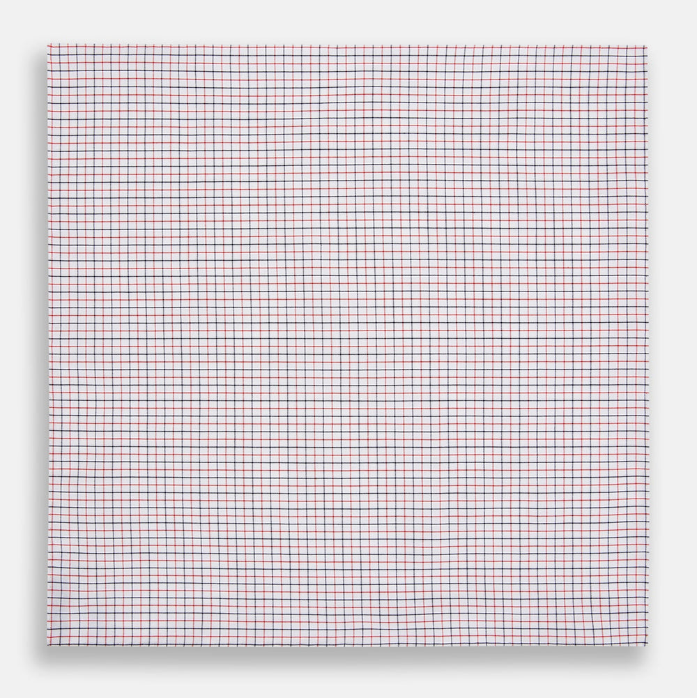 Turnbull & Asser’s Hand Rolled Red and Navy Graph Check Handkerchief—a white cotton accessory with red and navy grid lines, neatly folded for a touch of refined elegance.