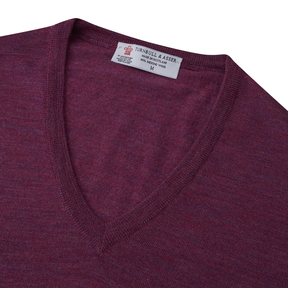 The Turnbull & Asser Plum Fine Merino V-Neck Jumper is a lightweight, long-sleeved layer in deep burgundy, featuring ribbed cuffs and hem for a refined finish, displayed against a white background.