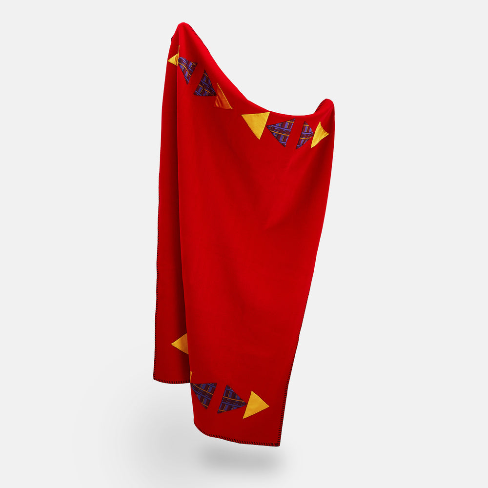 The Turnbull & Asser Red Applique Hand Stitched Lambswool Blanket features black-stitched edges and handsewn tie silk patches, including a yellow triangle and plaid triangle arranged to form a stylized fish.
