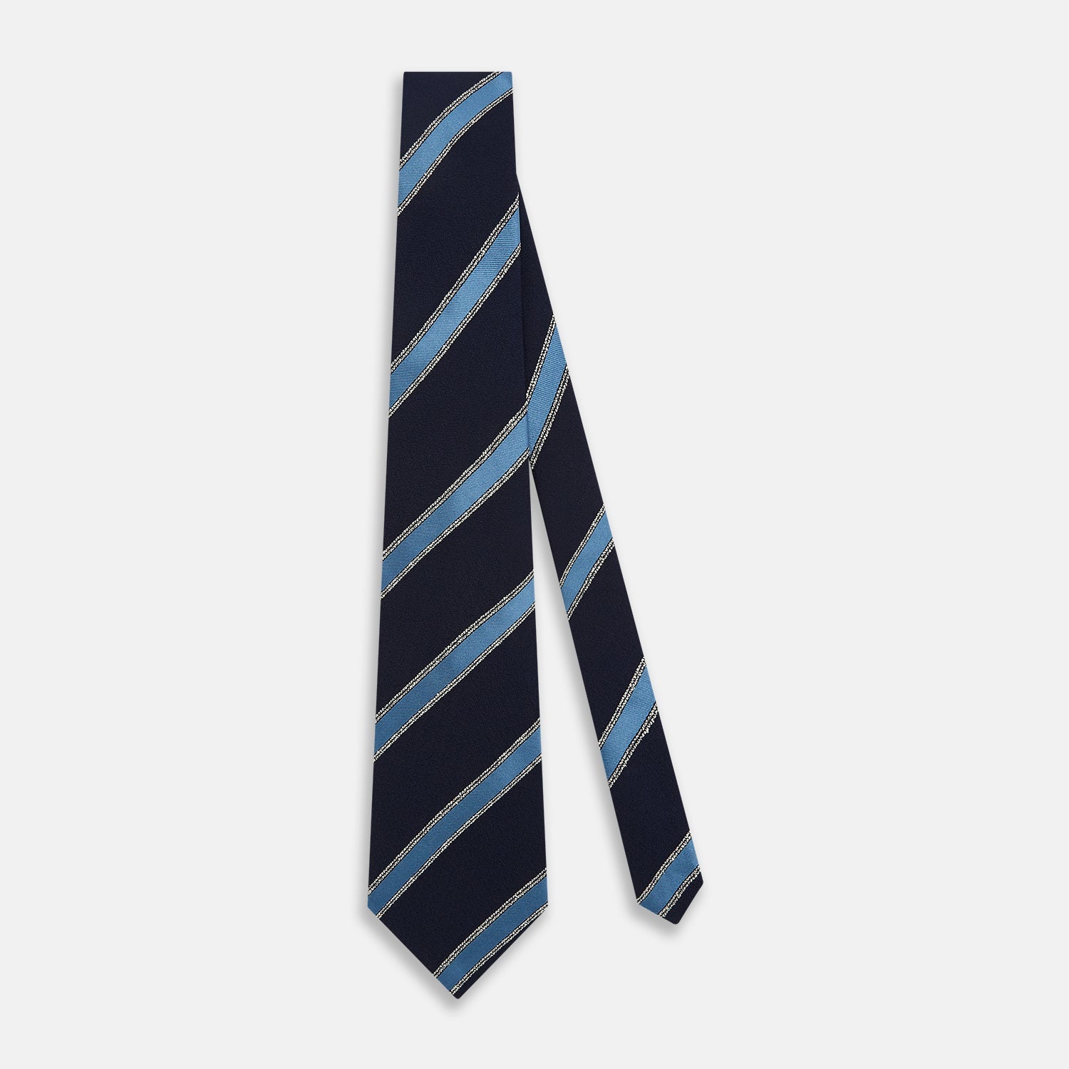 View 2 of product The Turnbull & Asser Navy Multi Stripe Silk Tie features diagonal light blue and silver stripes on an English silk navy base, rolled neatly against a white background.