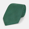 View 1 of product The Forest Green Geometric Floral Printed Silk Tie by Turnbull & Asser is shown rolled up on a white background, its English silk material featuring an elegant green and turquoise pattern.