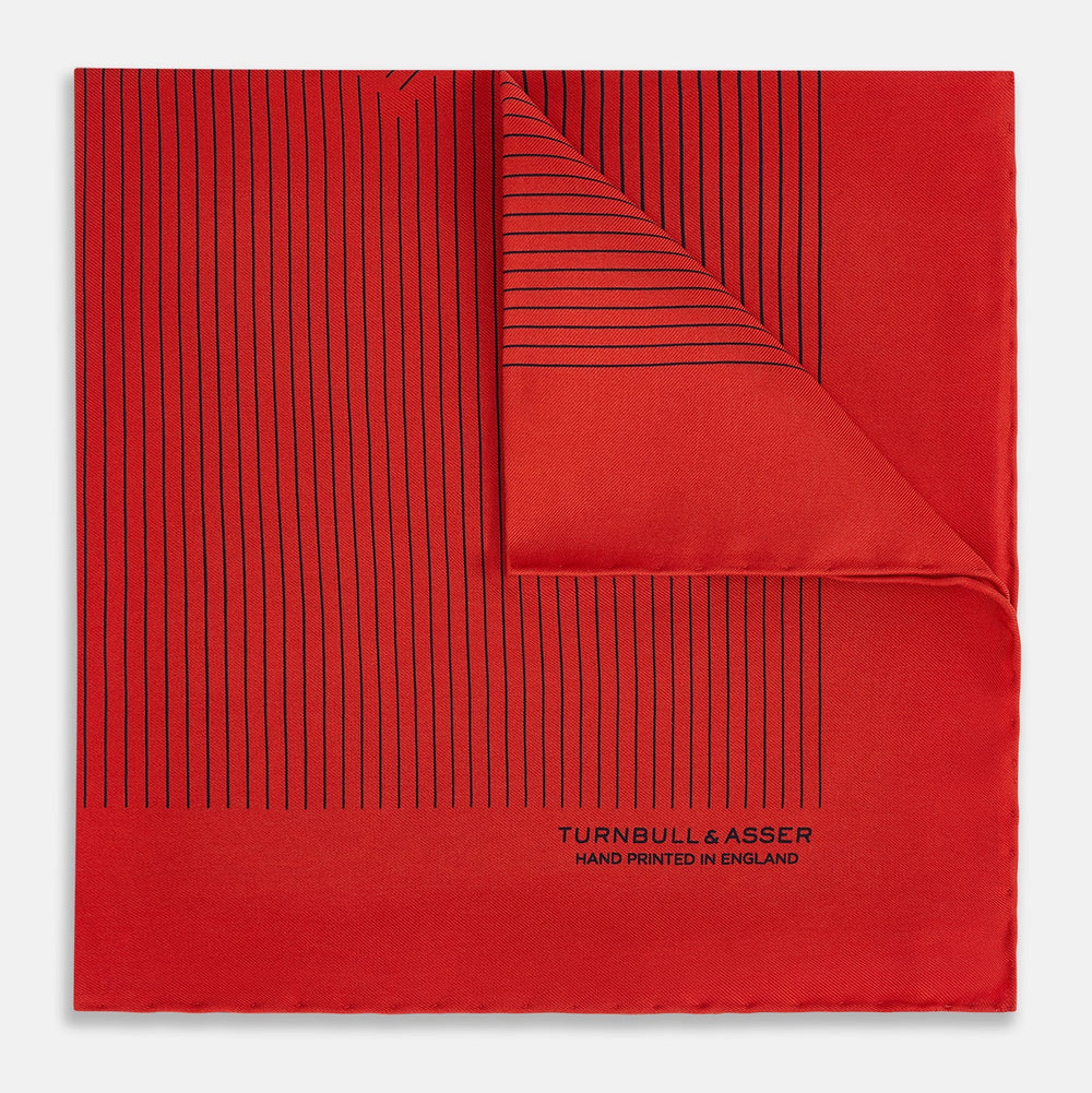 The Red Stripe Silk Pocket Square by Turnbull & Asser features thin black vertical lines and the brand signature in black on one corner, with a neatly folded edge for a touch of classic British style.