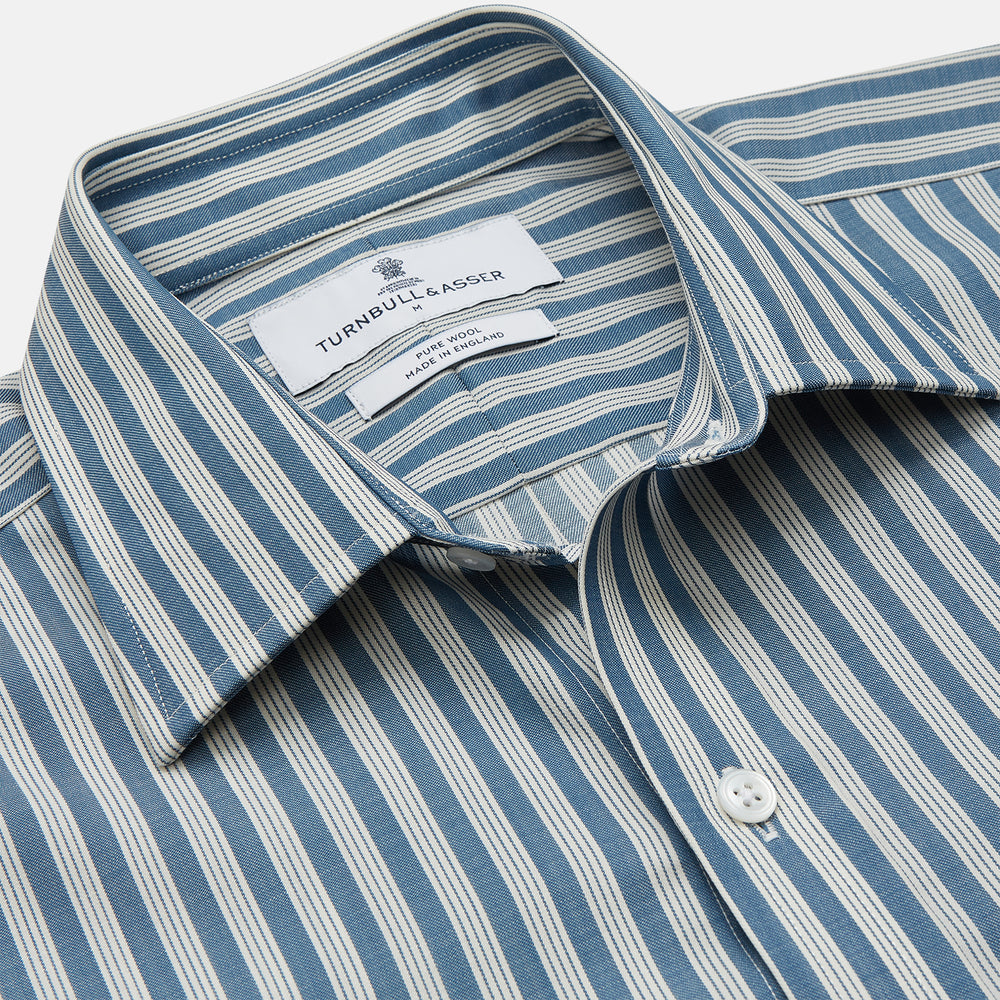 Turnbull & Asser’s Pale Blue Multi Stripe Weekend Fit Wool Shirt features a Derby collar, 1-button cuffs, and a chest pocket—ideal for casual layering. Shown laid flat on a white background for easy styling.