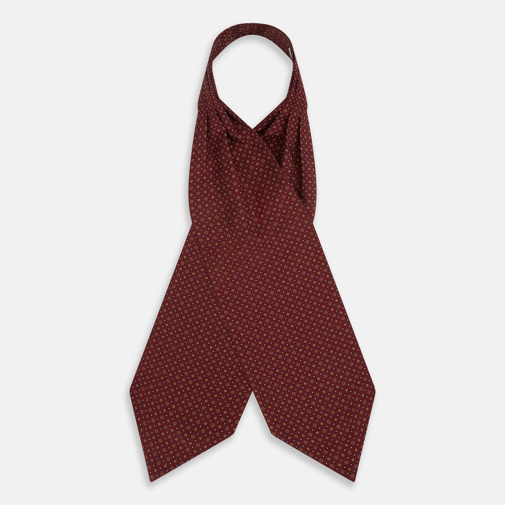 The Great Gatsby Burgundy Printed Silk Cravat by Turnbull & Asser features a maroon silk fabric with a small yellow and blue geometric pattern, subtle sheen, and neatly finished edges for an elegant, Gatsby-inspired formal accessory.