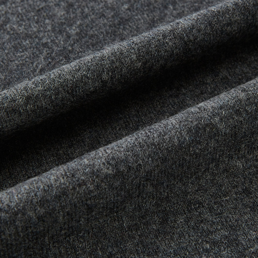 The Turnbull & Asser Plain Graphite Cashmere Knitted Scarf, draped and loosely knotted on a white background, showcases the refined elegance and timeless style of a luxury accessory.