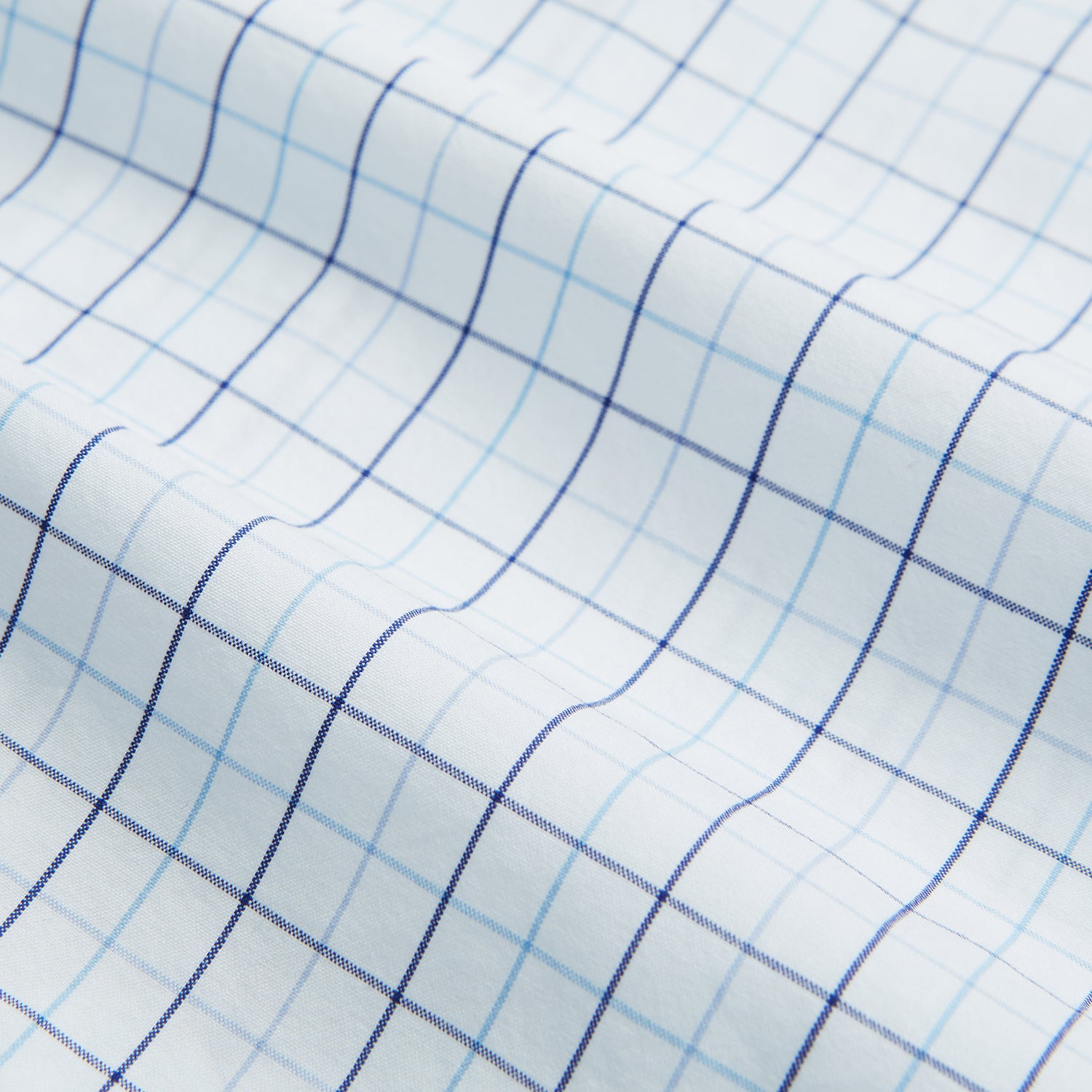 View 6 of product The Blue Overlay Grid Check Mayfair Shirt by Turnbull & Asser features a light blue and white grid check pattern with long sleeves and button-up design, making it a versatile wardrobe staple. Displayed on a plain white background.