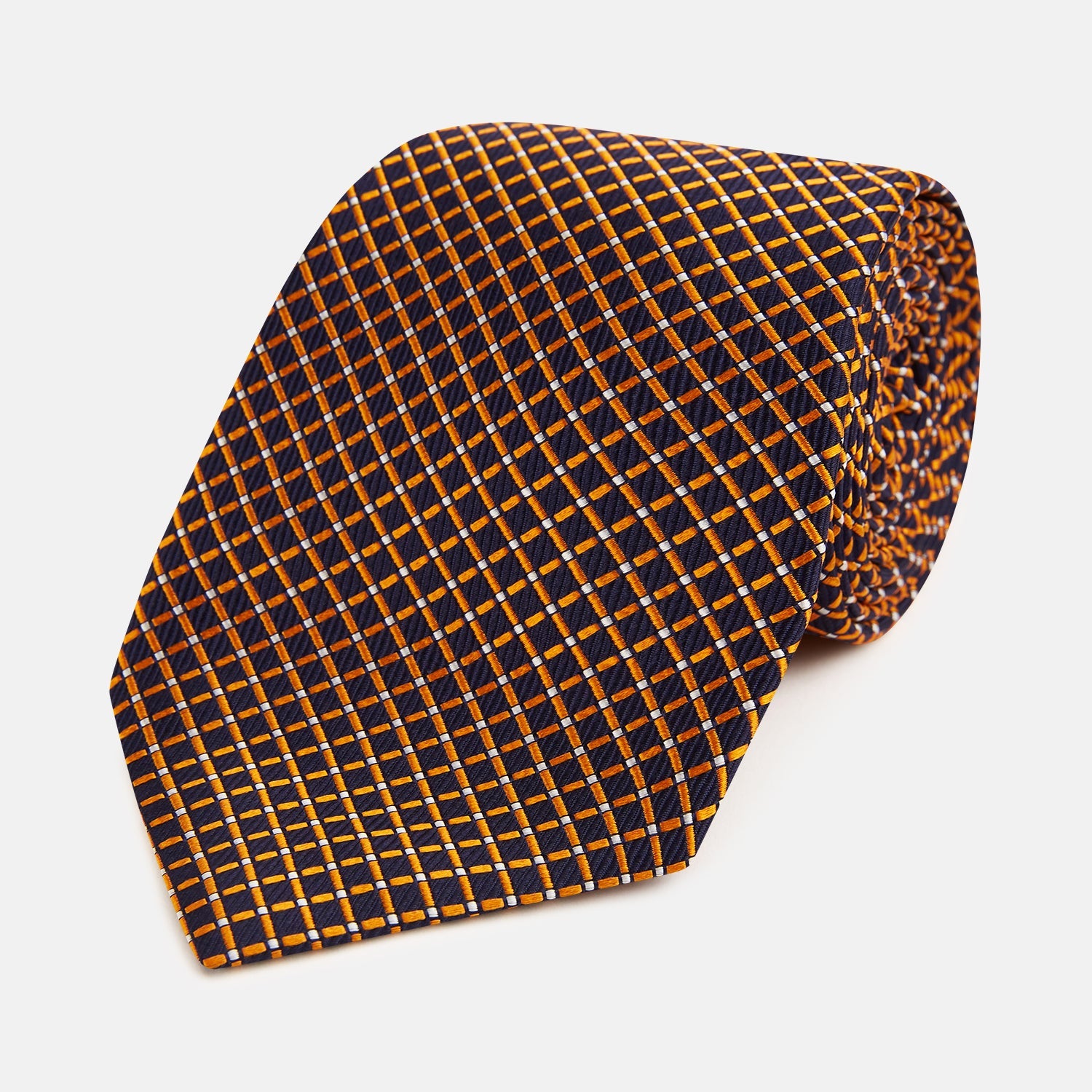 View 1 of product The Turnbull & Asser Orange and Navy Diamond Silk Tie features a yellow and orange diamond pattern on navy silk, ideal for modern office attire, and is displayed rolled up on a light surface.