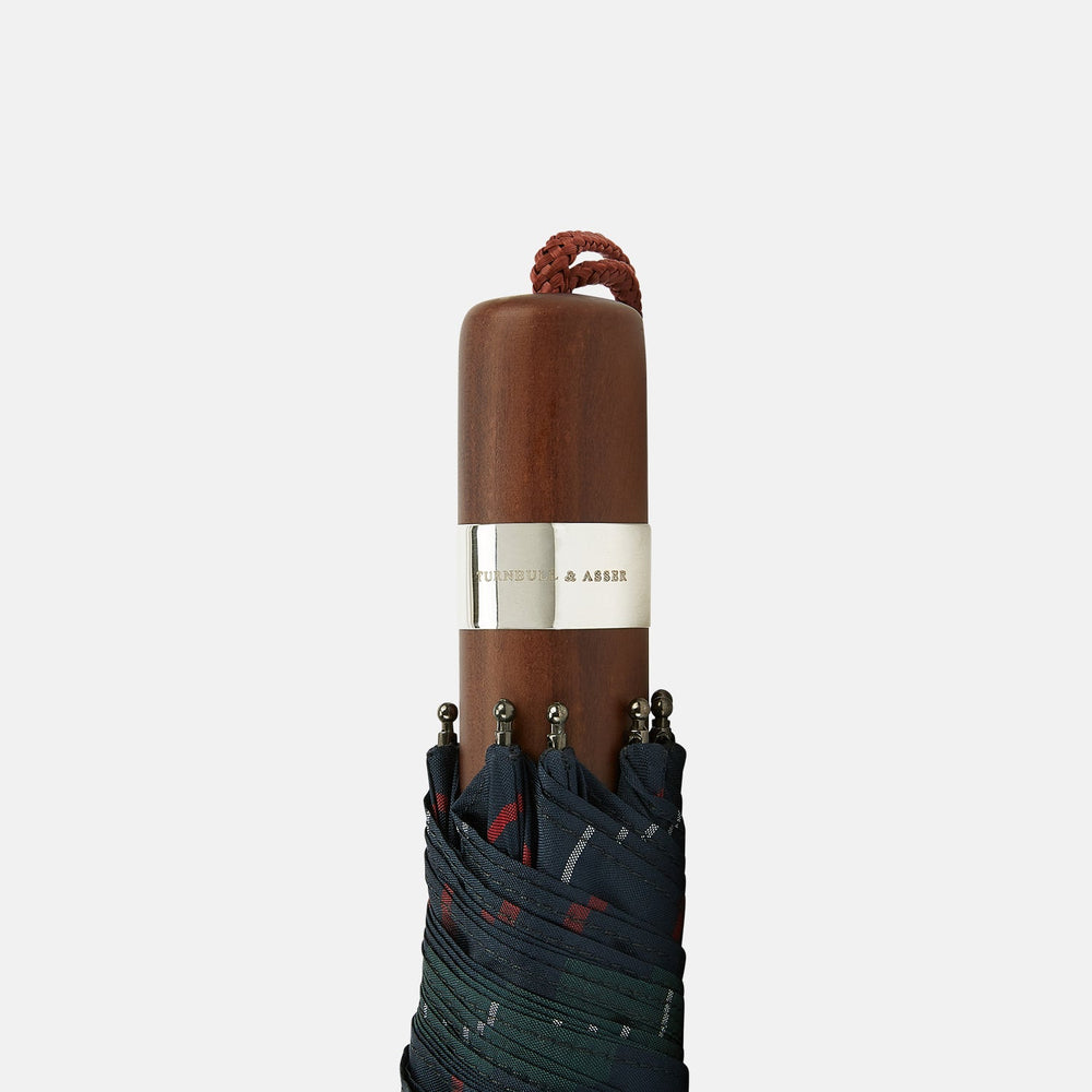 The Colquhoun Tartan Telescopic Umbrella by Turnbull & Asser features a green, blue, and red plaid canopy, silver metal shaft, and brown maple handle with wrist strap. Shown fully open against a plain white background.