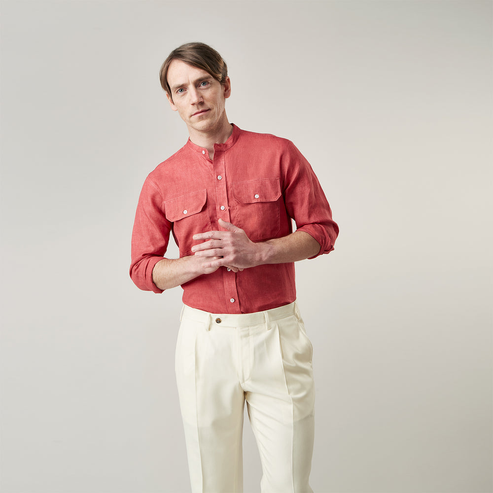 The Turnbull & Asser Plain Red Linen Weekend Fit Shirt with Stand Collar features long sleeves, a button-up front, and two buttoned-flap chest pockets. It is shown neatly laid flat on a plain light background.