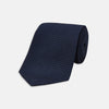 View 1 of product The Turnbull & Asser Navy Plain Woven Grenadine Silk Tie, an essential accessory, is rolled at one end and displayed on a plain white background.