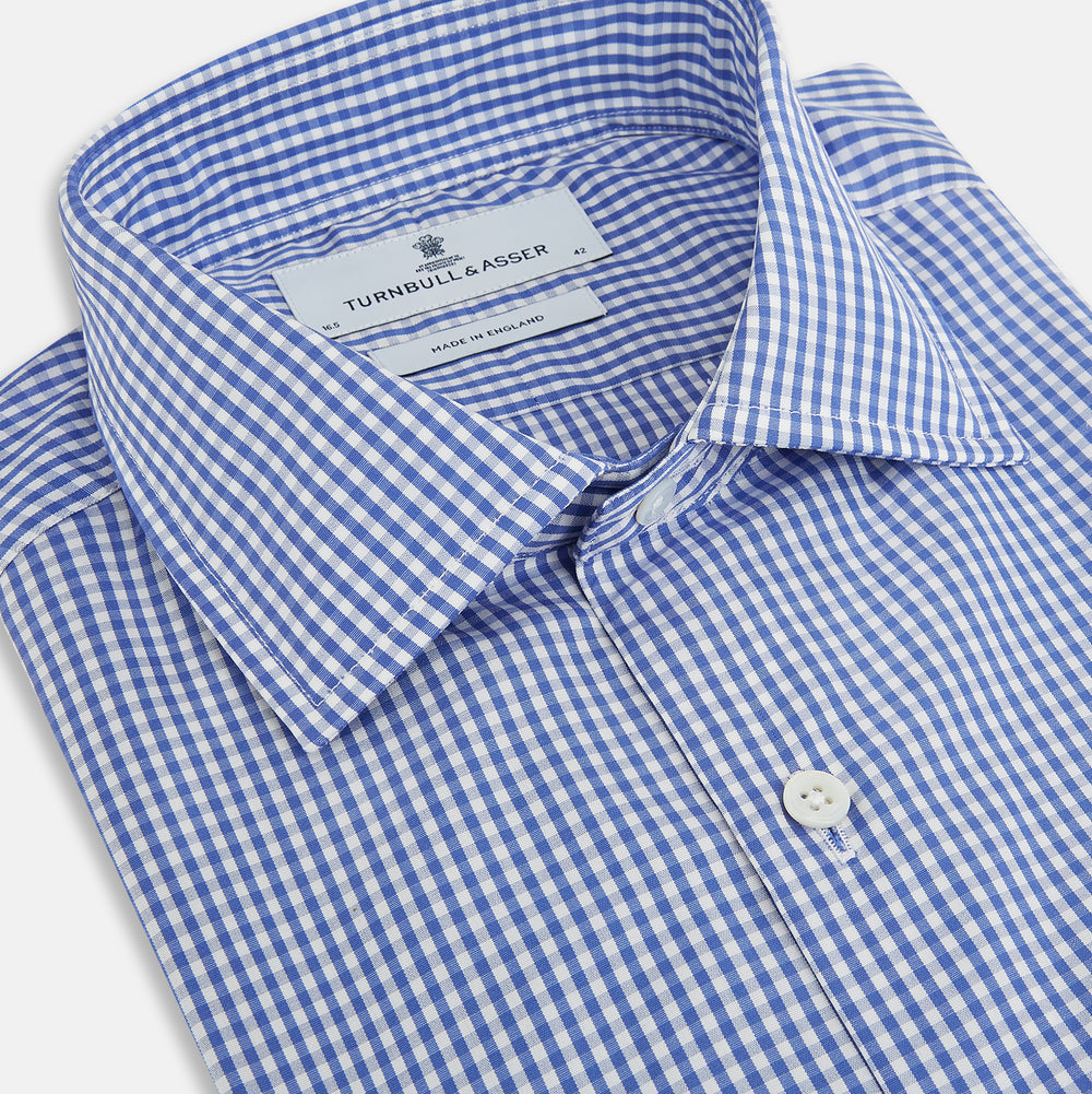 The Turnbull & Asser Blue Grid Check Belgravia Shirt, made from pure cotton with long sleeves, a spread collar, buttoned cuffs, and a blue-and-white check pattern, is laid flat on a white background.