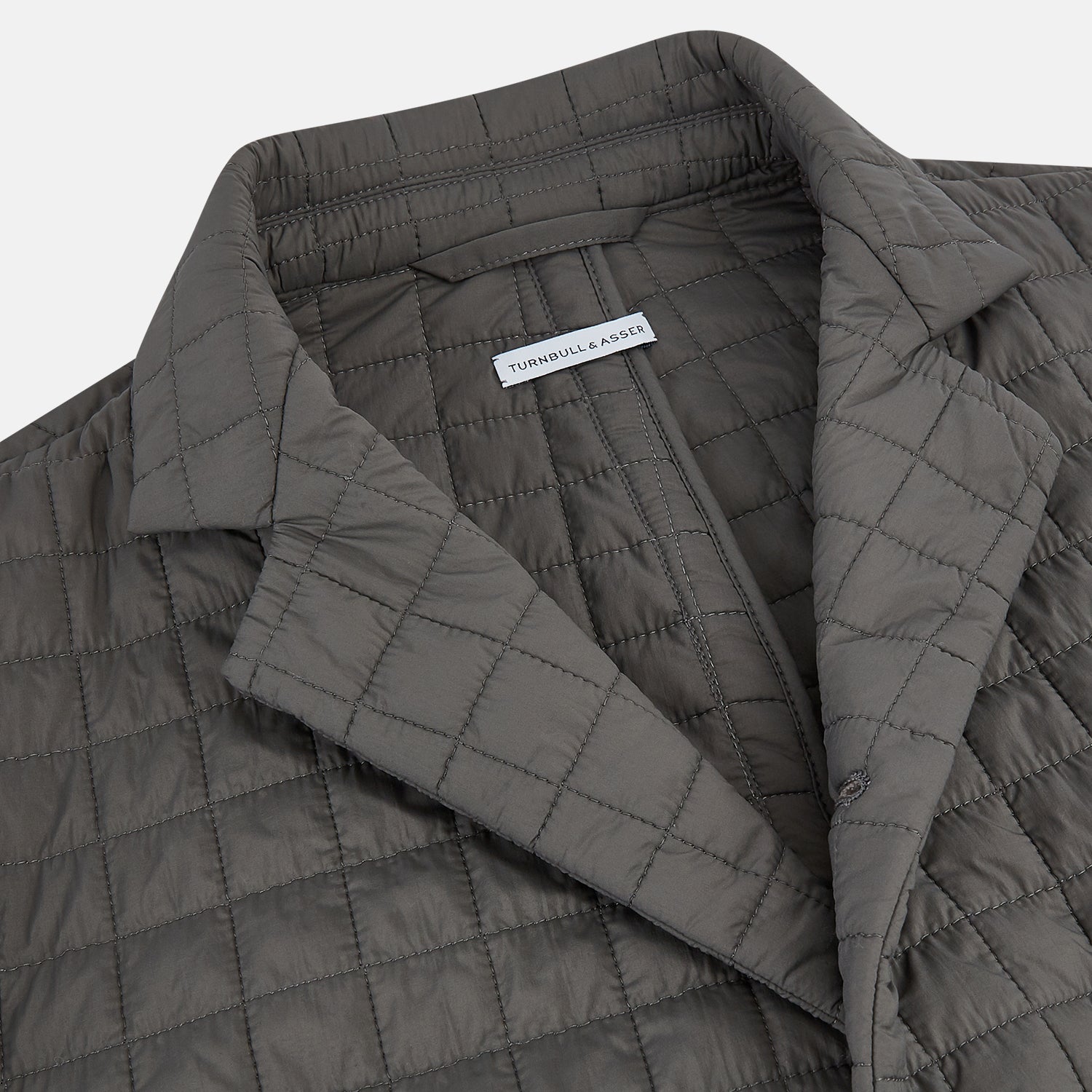 Image 2 of product The Fulham Shadow Grey Single-Breasted Quilted Blazer by Turnbull & Asser features a checkered pattern, notched lapel, three front buttons, chest pocket, and two flap pockets—ideal for formal wear on a plain white background.