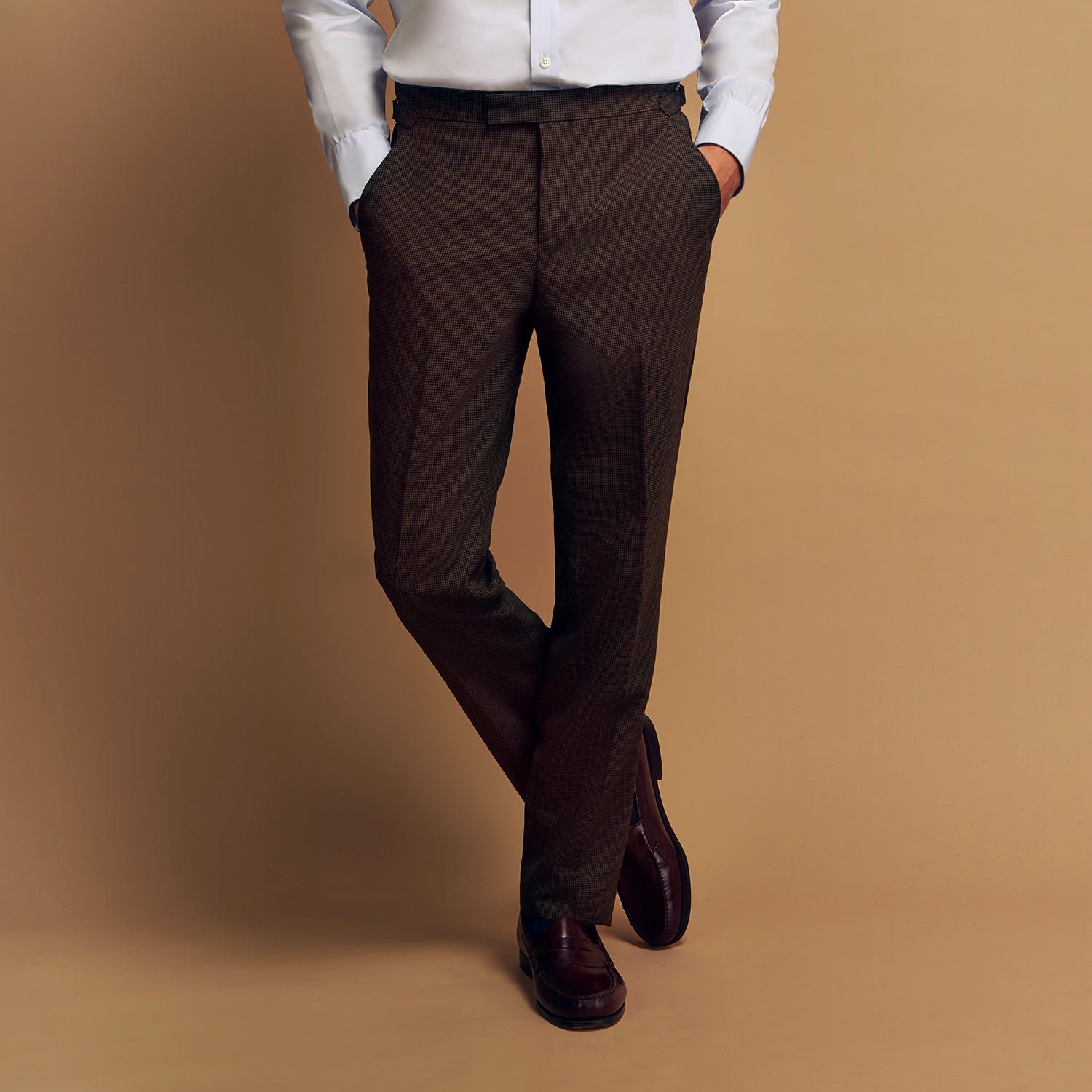 View 7 of product The Brown Puppytooth Wool Jonathan Trousers by Turnbull & Asser are straight-leg tailored trousers with belt loops, side pockets, and a front crease, shown on a white background.