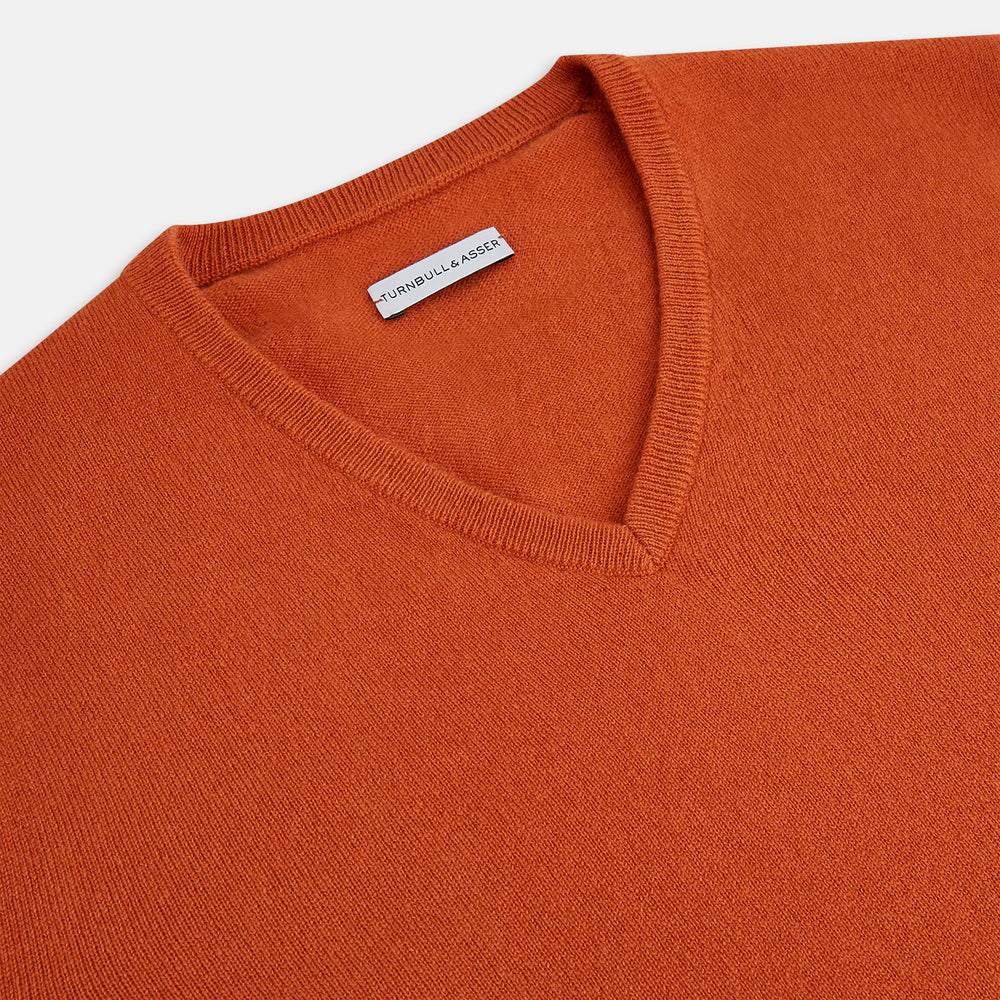 The Turnbull & Asser Rust Cashmere V-neck Jumper features long sleeves, ribbed cuffs and hem, and is shown against a plain white background.