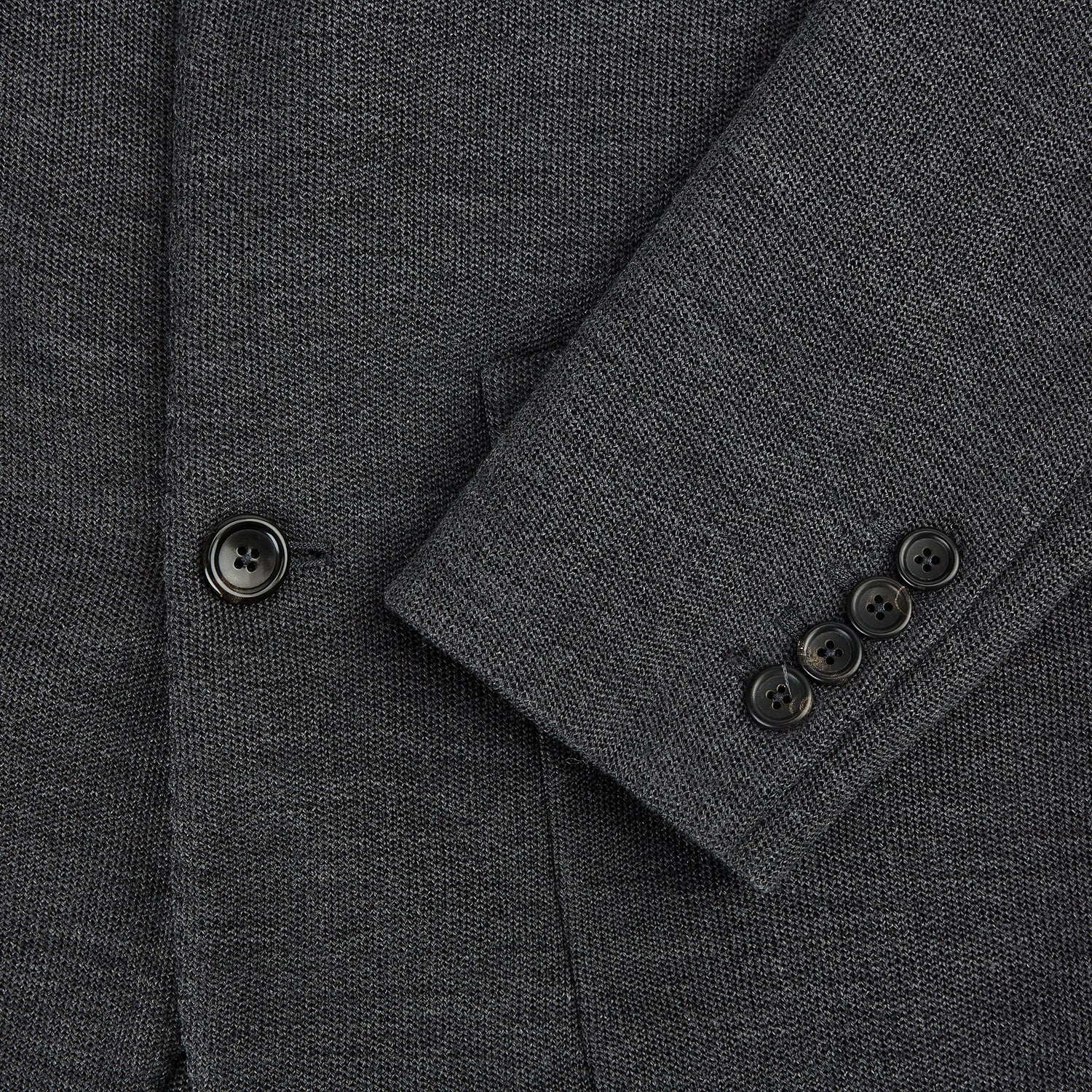 Image 4 of product The Turnbull & Asser Graphite Knitted Oxford Blazer for men features a dark gray hue, two buttons, notched lapels, and three front pockets—a modern British-inspired piece styled elegantly against a light background.