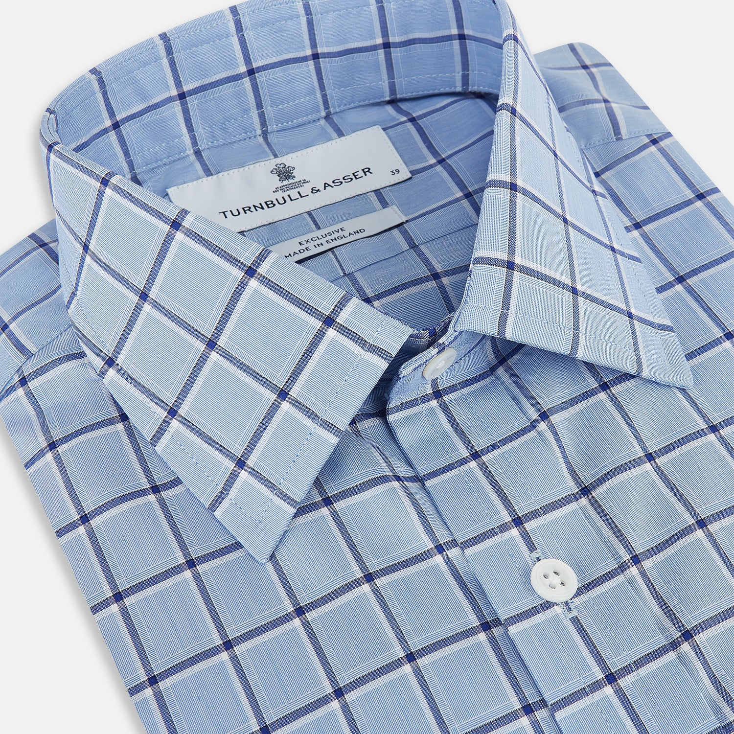 Image 2 of product The Turnbull & Asser Blue and Navy Windowpane Mayfair Shirt features long sleeves, a T&A collar, buttoned cuffs, and Italian cotton in a blue and navy windowpane pattern, shown on a plain white background.