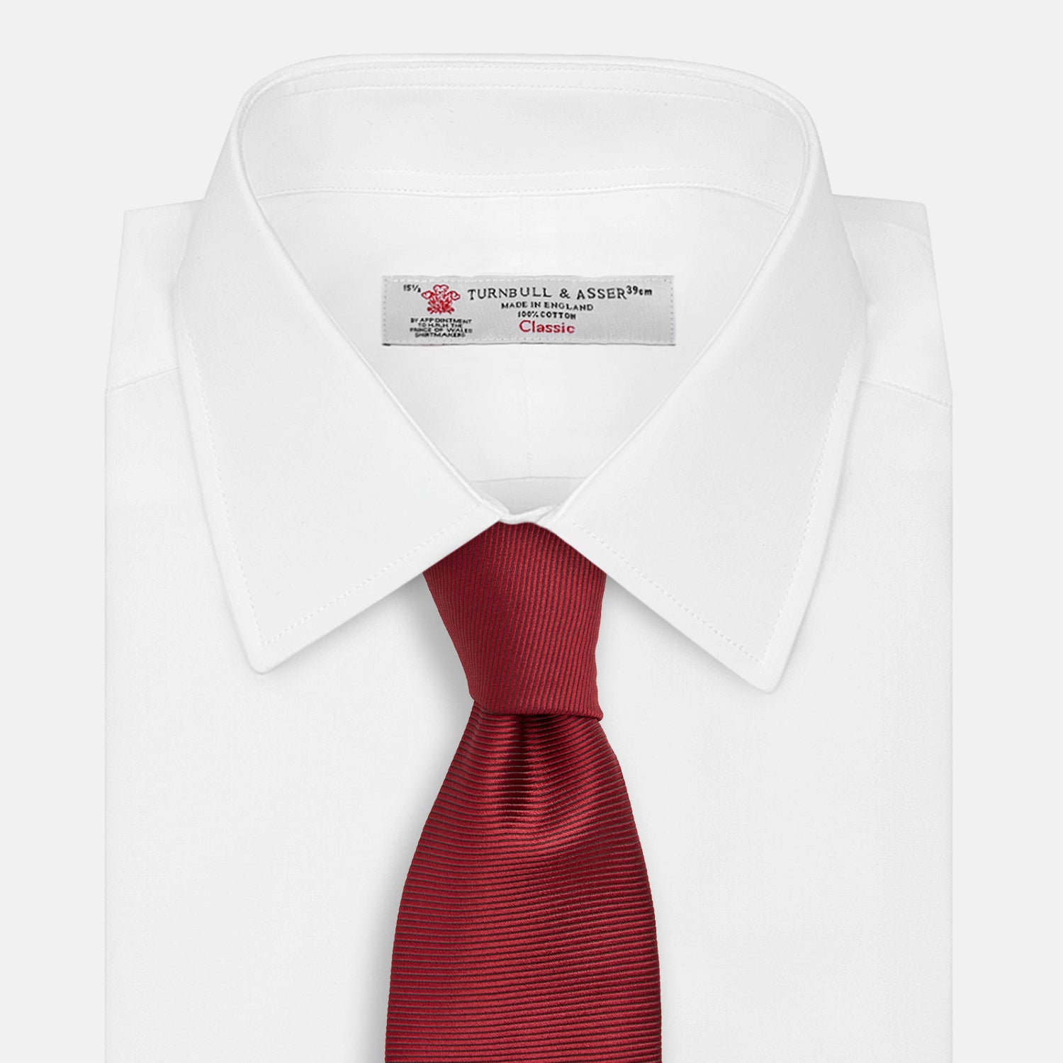 View 2 of product The HORIZONTAL TWILL BURGUNDY TIE by Turnbull & Asser features a subtle textured pattern in solid burgundy, rolled neatly and displayed against a white background—a versatile addition to any gentleman’s wardrobe.