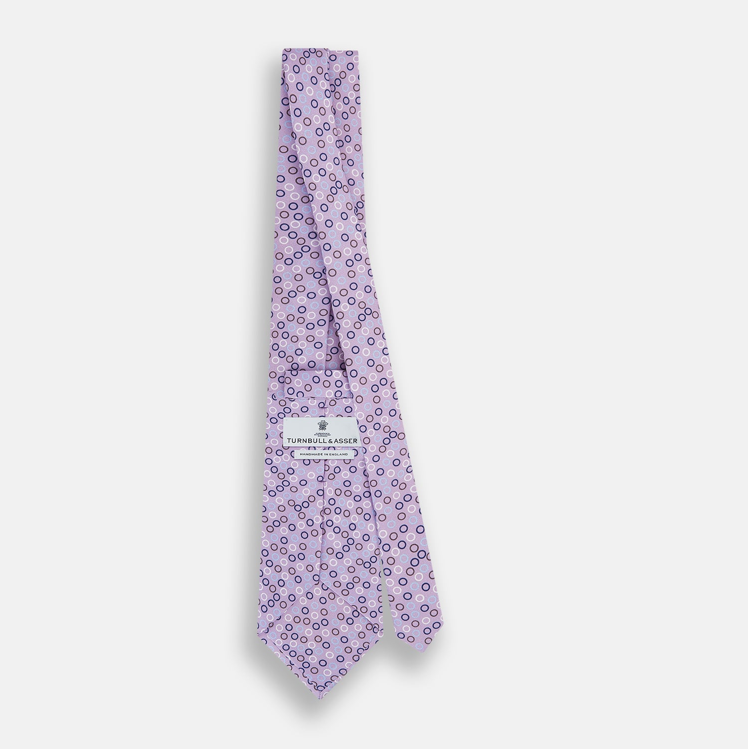 View 4 of product The Turnbull & Asser Multi-coloured Circle Lilac Silk Tie features overlapping blue, purple, and white circles on fine English silk—ideal for elevating smart outfits. Shown rolled against a plain white background.