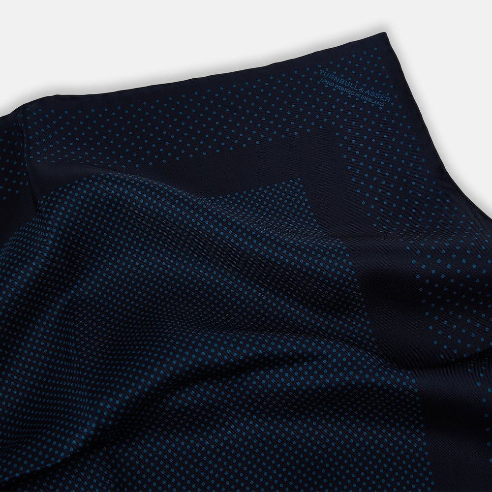 The Turnbull & Asser Navy and Blue Dot Silk Pocket Square features a handmade design in navy silk with small light blue dots and a crisp border, finished with one corner folded to display the reverse side.