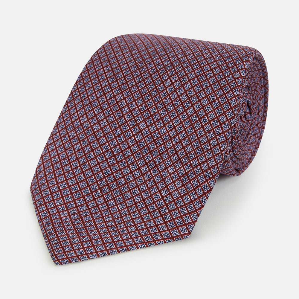 The Turnbull & Asser Indies Red Floral Square-Print Silk Tie is shown rolled up, highlighting its red floral square pattern against a plain white background.