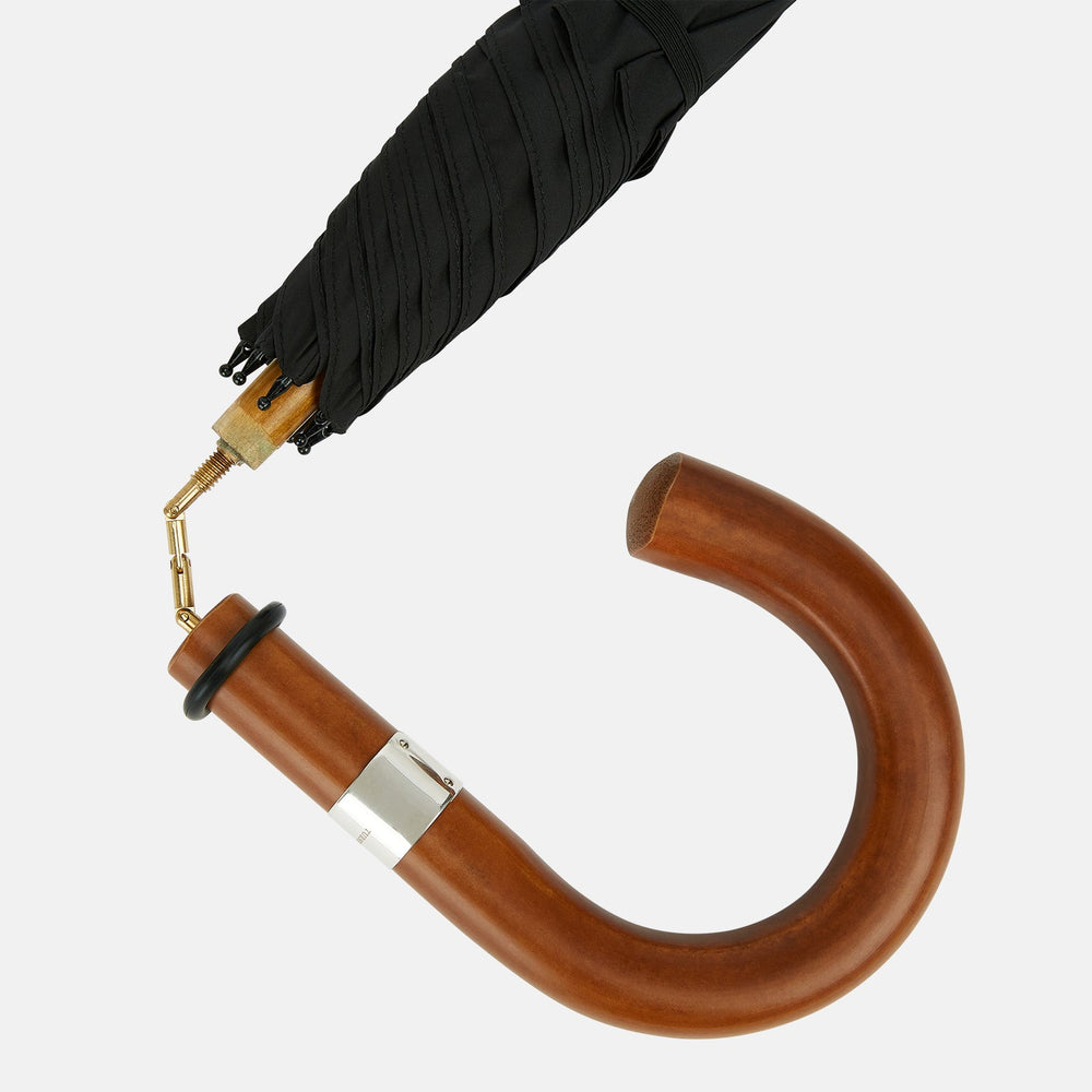The Turnbull & Asser Black Traveller Umbrella features a Malacca crook handle and straight wooden shaft—a timeless accessory displayed fully opened against a white background.
