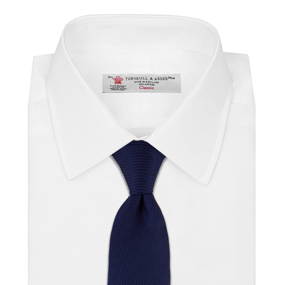 The Turnbull & Asser Seven-Fold Navy Lace Silk Tie is shown on a white background, rolled at one end with the pointed tip facing forward.