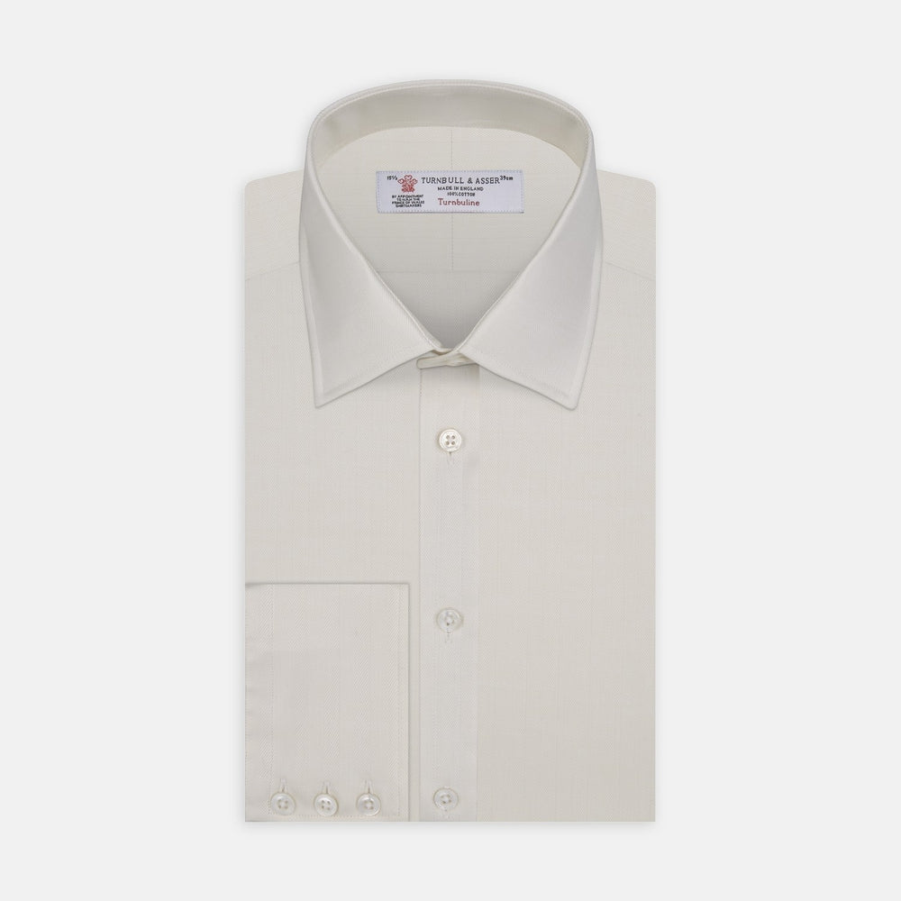 Close-up of Turnbull & Asser's Cream Herringbone Cotton Fabric, featuring gentle folds and a smooth, slightly shiny texture within a circular frame.