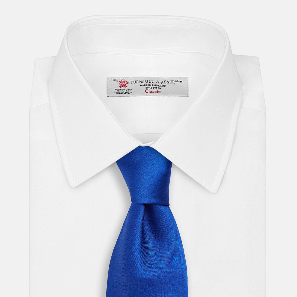 The Turnbull & Asser SATIN CRUISE TIE, in vibrant royal blue with a smooth, lustrous finish, creates a striking contrast against a plain white background.