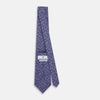 View 4 of product The Turnbull & Asser Lilac Paisley Silk Tie is shown rolled up, featuring a blue paisley pattern on a light purple background and displayed on a white surface.