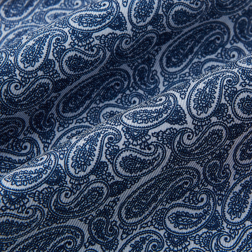 The Pale Blue Paisley Silk Cravat by Turnbull & Asser showcases intricate, swirling blue and white paisley designs on a light background, echoing the elegance of British style accessories.