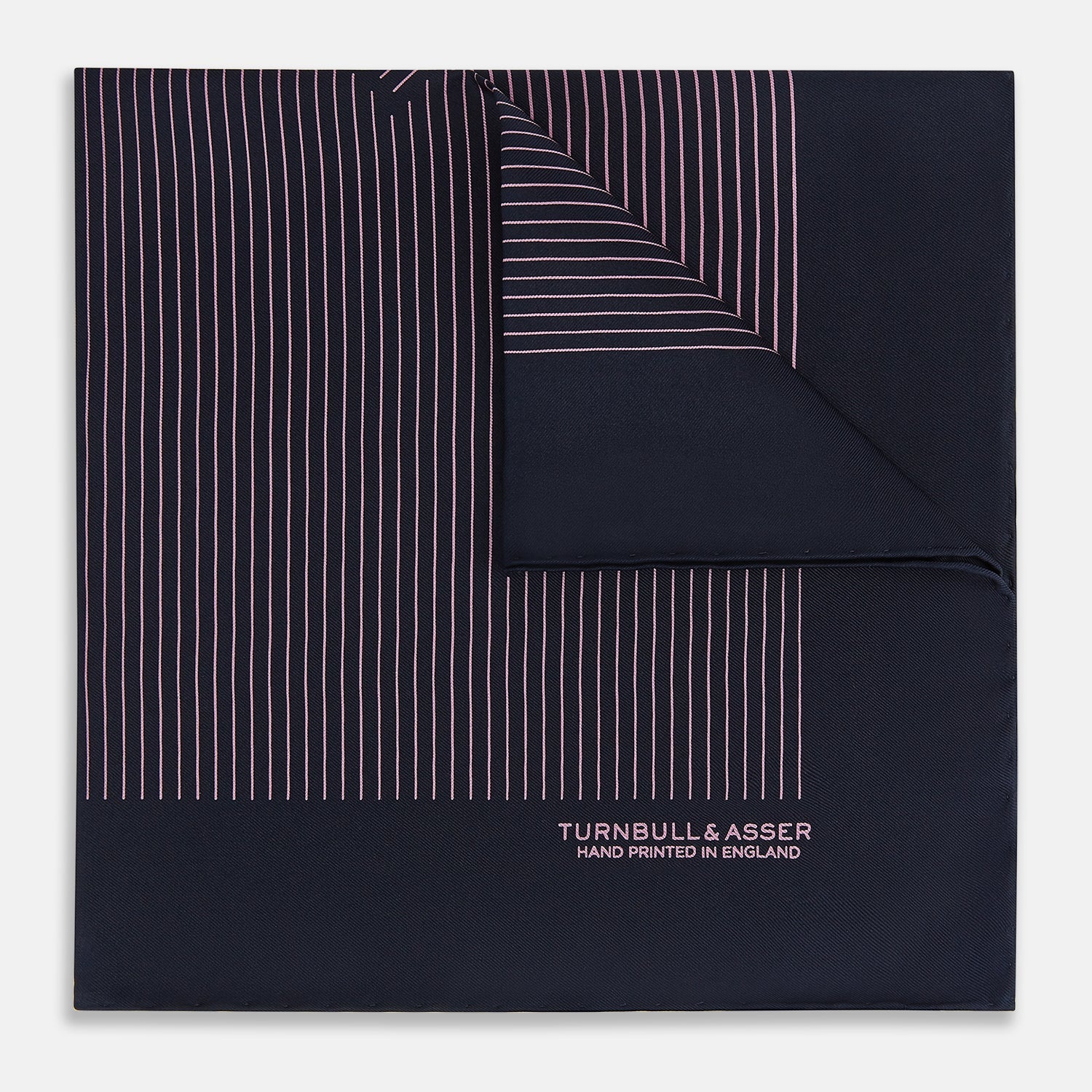 View 1 of product The Navy and Pink Stripe Silk Pocket Square by Turnbull & Asser features thin pink stripes, a geometric border, hand-rolled edges, and "TURNBULL & ASSER HAND PRINTED IN ENGLAND" printed in white.