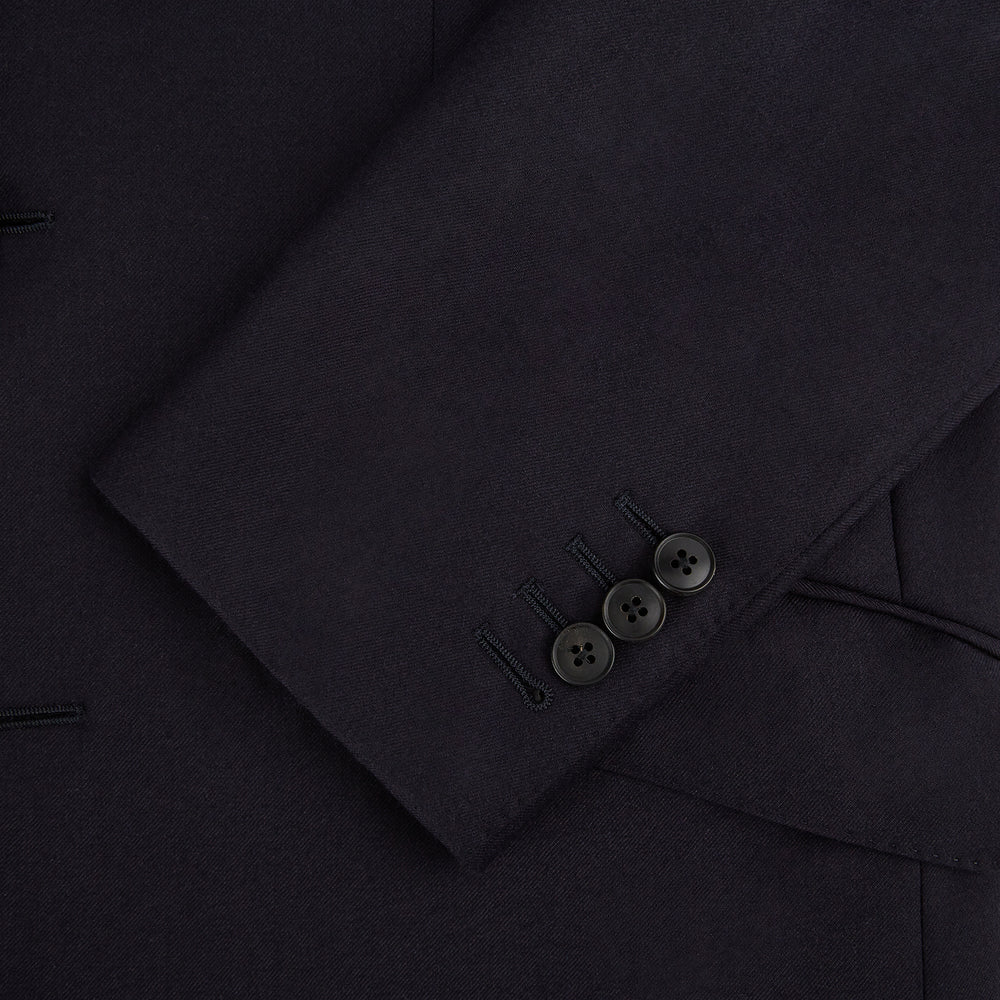 The Turnbull & Asser Short Navy Single Breasted Suit is shown flat on a white background, with a notch lapel jacket featuring two front pockets and matching trousers neatly folded underneath.