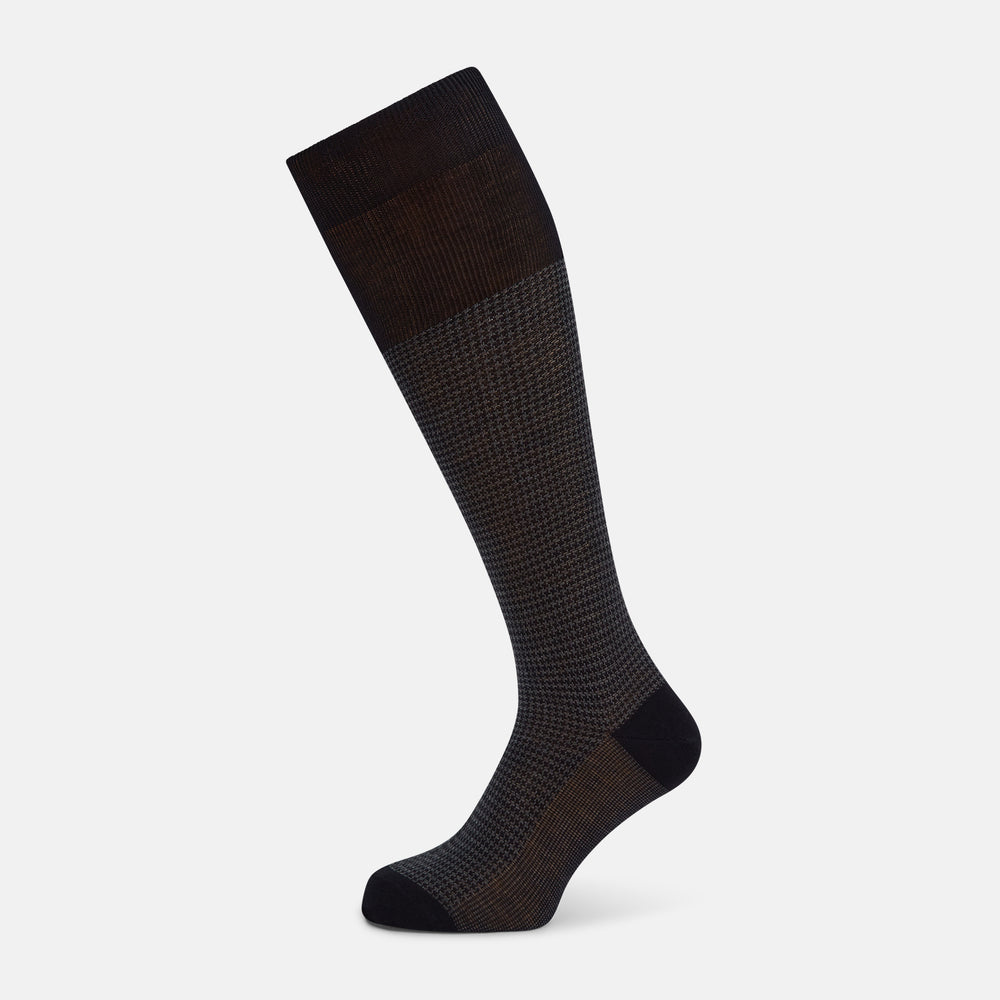 The Turnbull & Asser Charcoal Melange Houndstooth Long Sock is knee-high, with a subtle dark houndstooth pattern and solid black toe, heel, and cuff, shown on a white background.