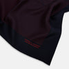 View 2 of product The Turnbull & Asser Navy and Red Stripe Silk Pocket Square features thin red stripes on navy silk, with "HAND PRINTED IN ENGLAND" in red at the corner. A folded corner shows its hand-rolled edges and refined design.