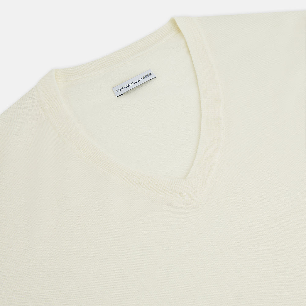 The Turnbull & Asser White Fine Merino V-Neck Jumper, shown against a white background, features a timeless design with long sleeves and ribbed cuffs and hem.