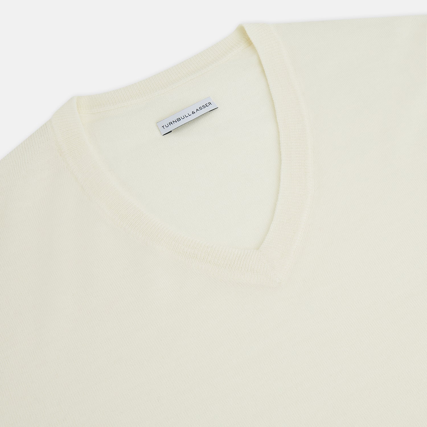 View 7 of product The Turnbull & Asser White Fine Merino V-Neck Jumper, shown against a white background, features a timeless design with long sleeves and ribbed cuffs and hem.