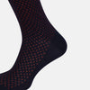 View 4 of product The Turnbull & Asser Navy/Red Motif Long Sock is crafted from mercerised Egyptian cotton, featuring a subtle red and navy diamond pattern with a solid navy cuff, heel, and toe, displayed on a white background.
