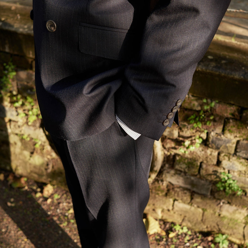 The Turnbull & Asser Navy Wool Pinstripe Double-Breasted Jacket features peak lapels, four front buttons, and three front pockets, and is displayed on a plain white background.