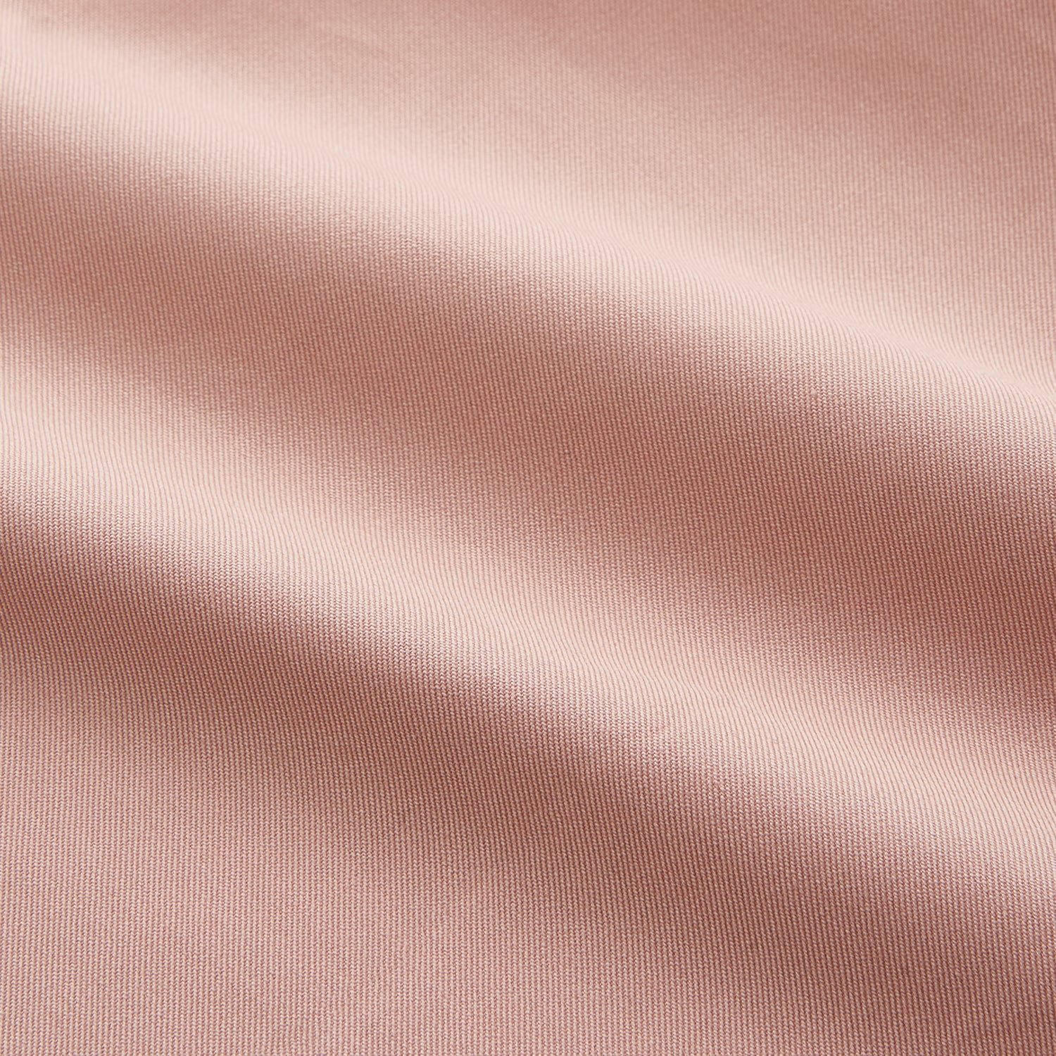 View 5 of product A man faces forward in a relaxed pose against a beige background, wearing the Turnbull & Asser Pink Piece Dyed Weekend Fit Suffolk Shirt with a button-down collar, dark cuffed jeans, and black shoes.