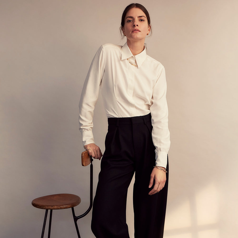 The Cream Silk Tailored Bianca Shirt by Turnbull & Asser features long sleeves, a pointed collar, and curved hem in soft-touch peace silk with a tailored fit. Shown laid flat on a white background.
