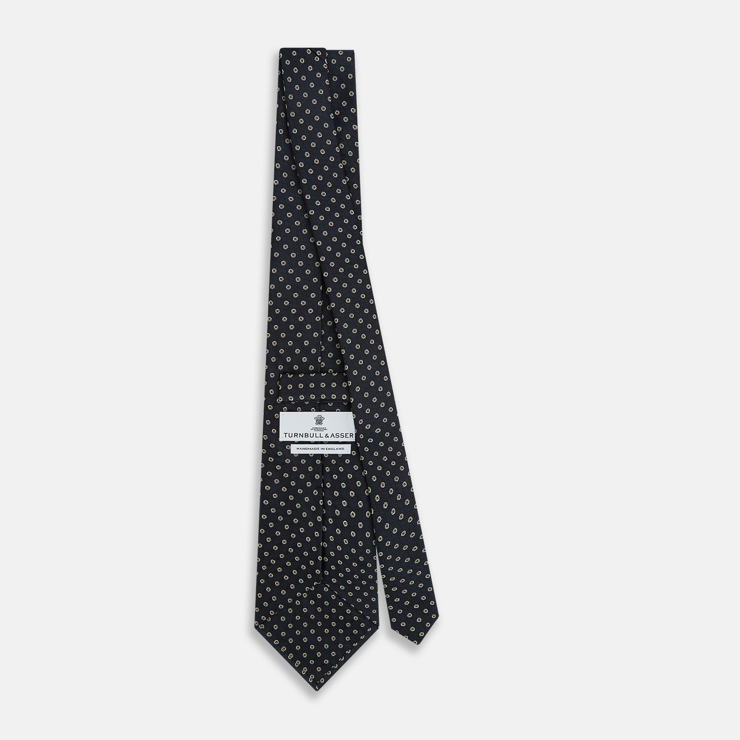 View 4 of product The Turnbull & Asser Navy and White Circle Silk Tie features a repeating circle pattern and is shown rolled on a white background—a timeless men's accessory for any occasion.