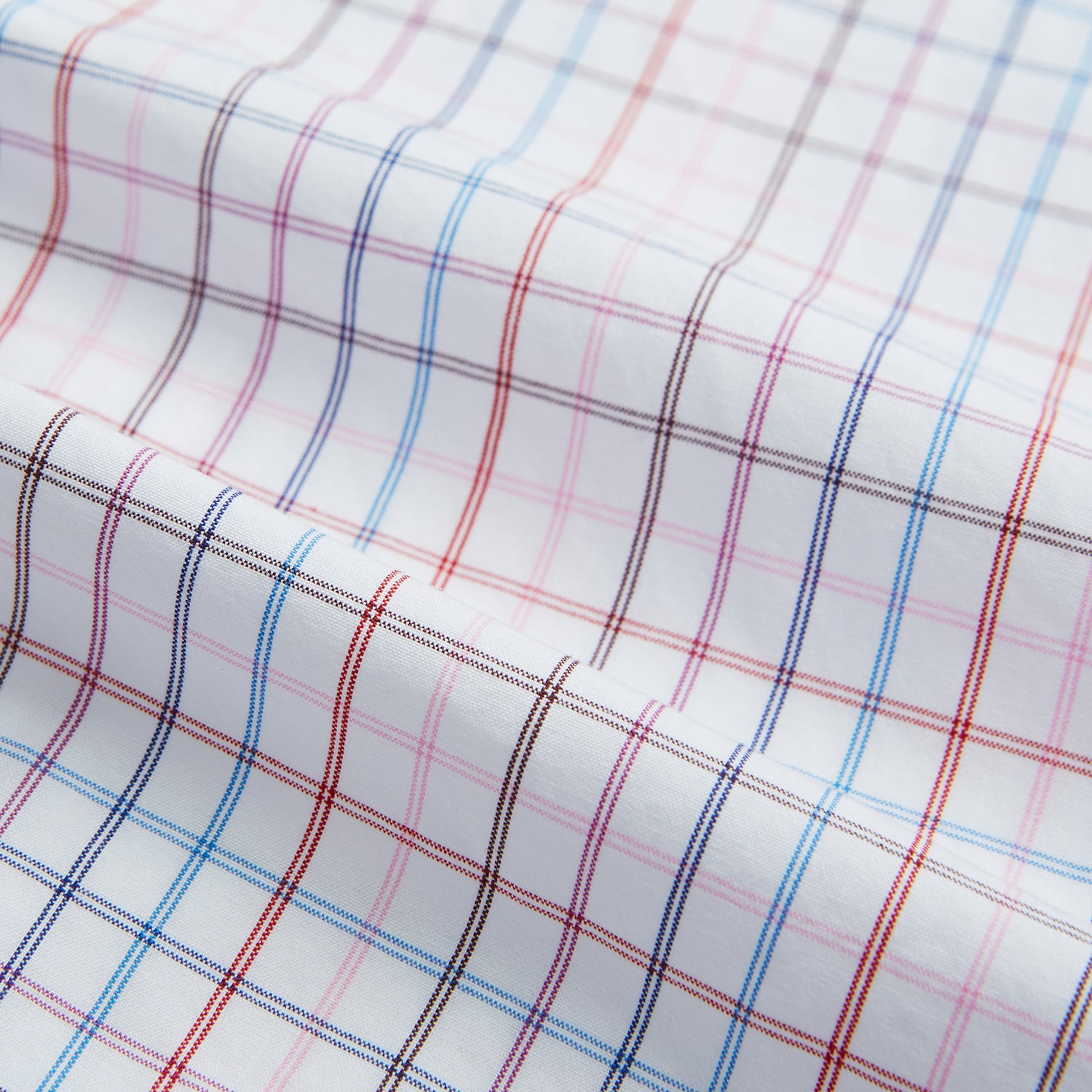 View 6 of product The Turnbull & Asser Pink Multi Double Grid Check Mayfair Shirt, made from organic cotton with a pointed collar and buttoned cuffs, features a light pink base with blue and red grid checks and is shown flat on a white background.