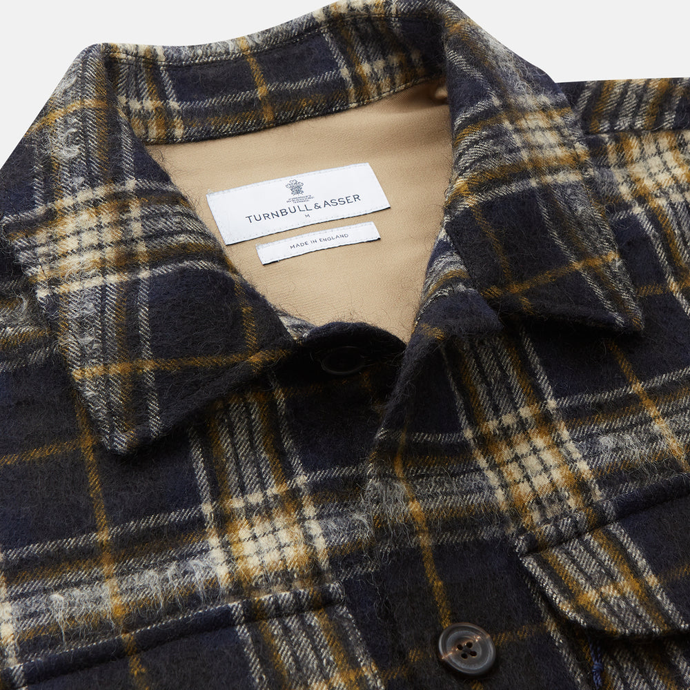The Turnbull & Asser Navy and Beige Check Wool and Mohair Blend Somerset Overshirt, featuring long sleeves, two chest pockets, and a classic collar, is laid flat on a white background.