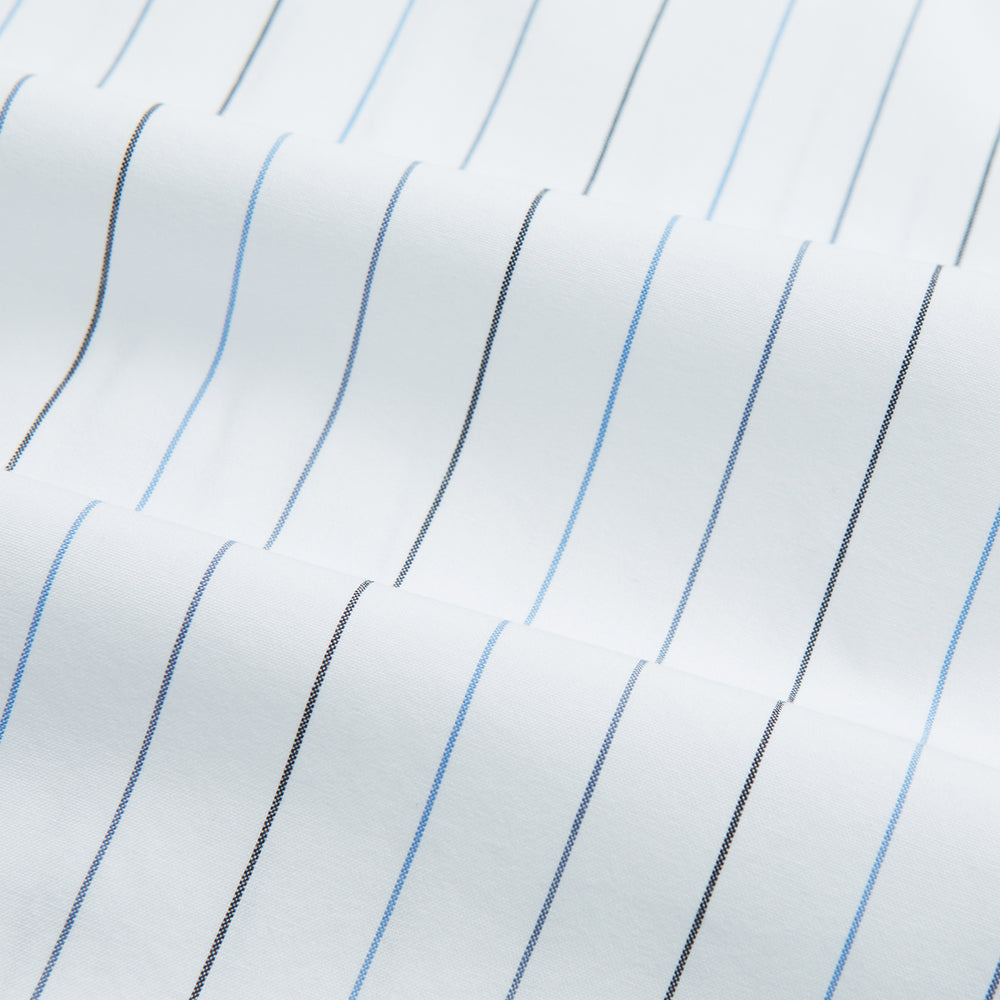 The Blue Wide Pinstripe Mayfair Shirt by Turnbull & Asser is a contemporary long-sleeve button-down with a collar, crafted from white fabric with bold vertical blue pinstripes. It is displayed neatly on a plain white background.