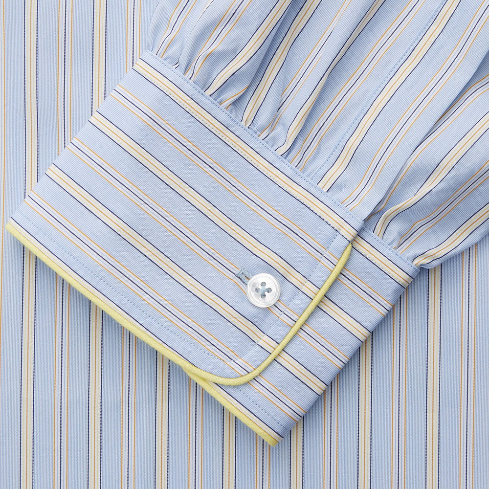 The Turnbull & Asser Blue and Yellow Stripe Poplin Cotton Nightshirt features light blue and yellow vertical stripes, long sleeves, a classic collar, single chest pocket, rounded hem, and is displayed flat on a white background.