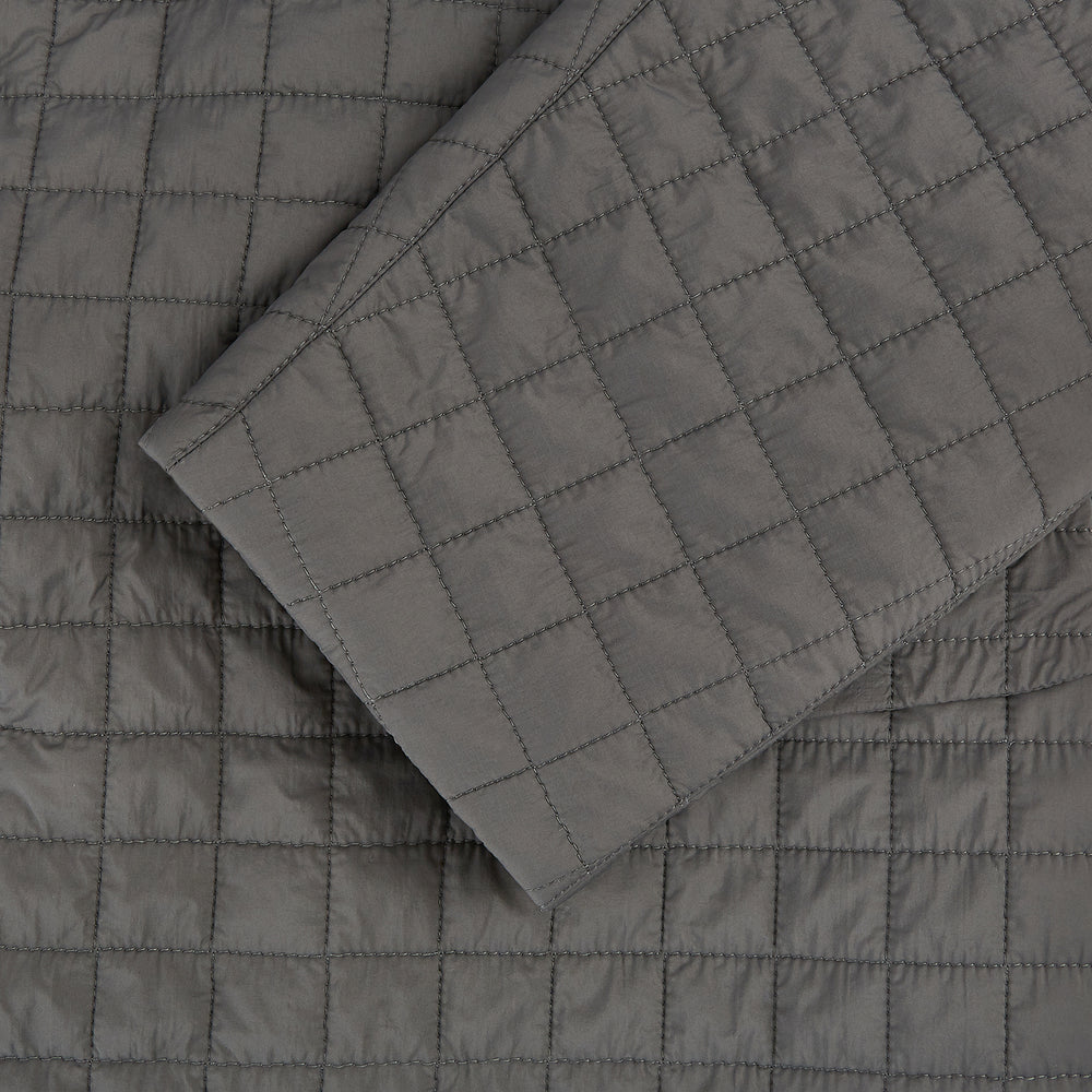 The Fulham Shadow Grey Single-Breasted Quilted Blazer by Turnbull & Asser features a checkered pattern, notched lapel, three front buttons, chest pocket, and two flap pockets—ideal for formal wear on a plain white background.