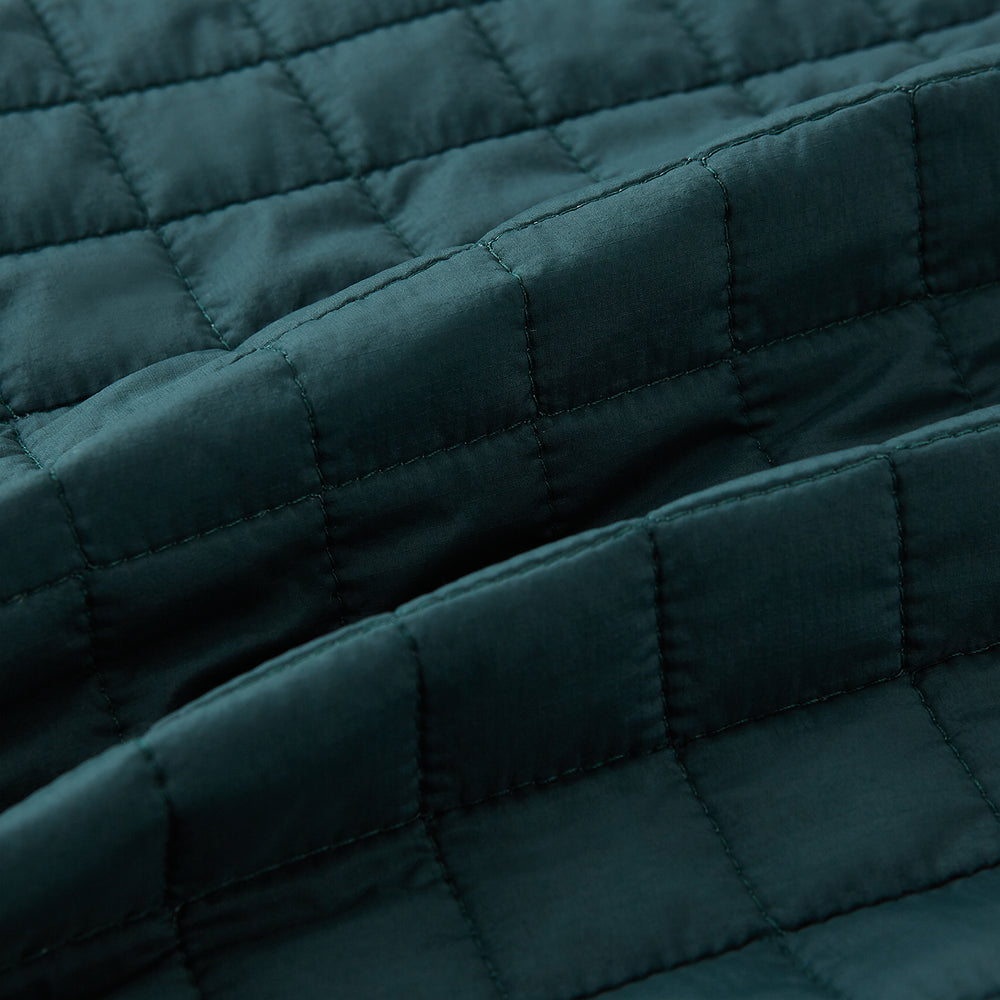 The Turnbull & Asser Forest Green Double-Breasted Quilted Gilet features black buttons, a chest pocket, two zippered side pockets, and an overlapping collar—ideal for layered dressing against a plain white background.
