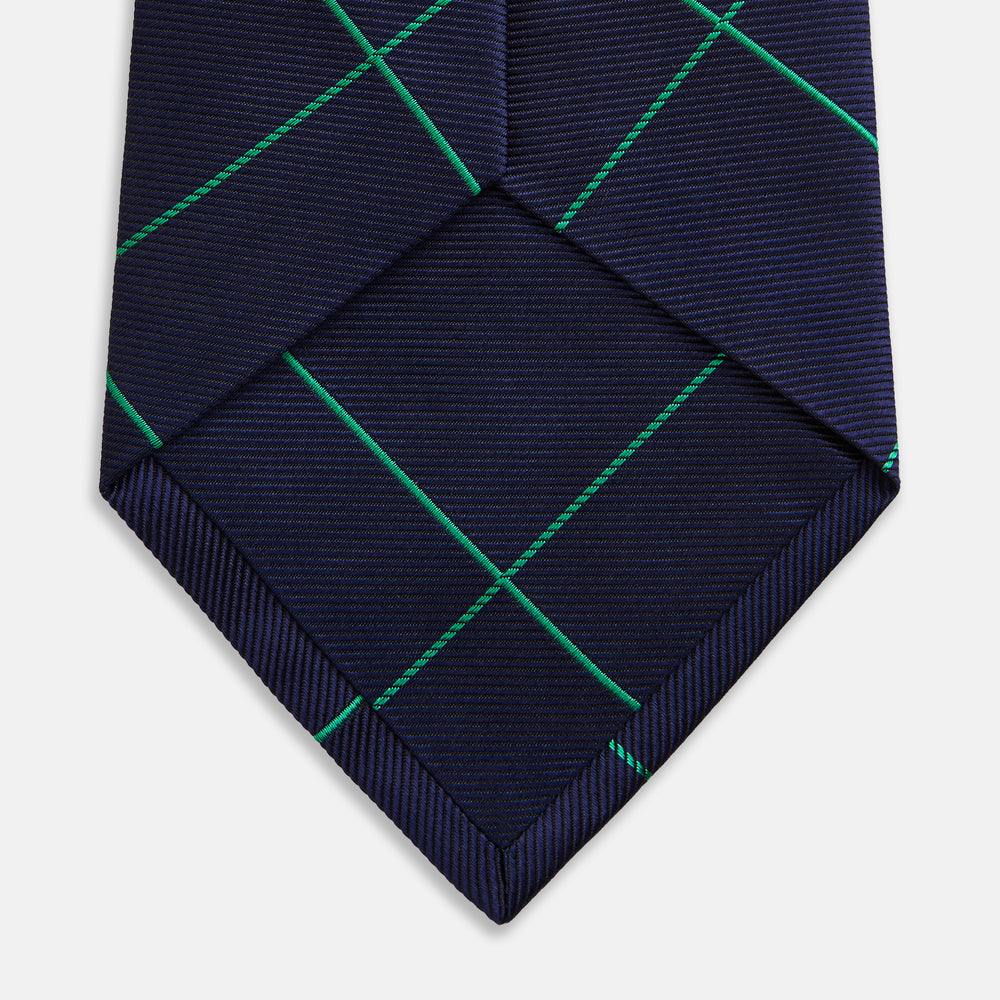 The Turnbull & Asser Green and Navy Window Pane Silk Tie features a subtle ribbed texture with a diagonal green grid pattern, inspired by archival designs—a stylish choice for modern office attire.